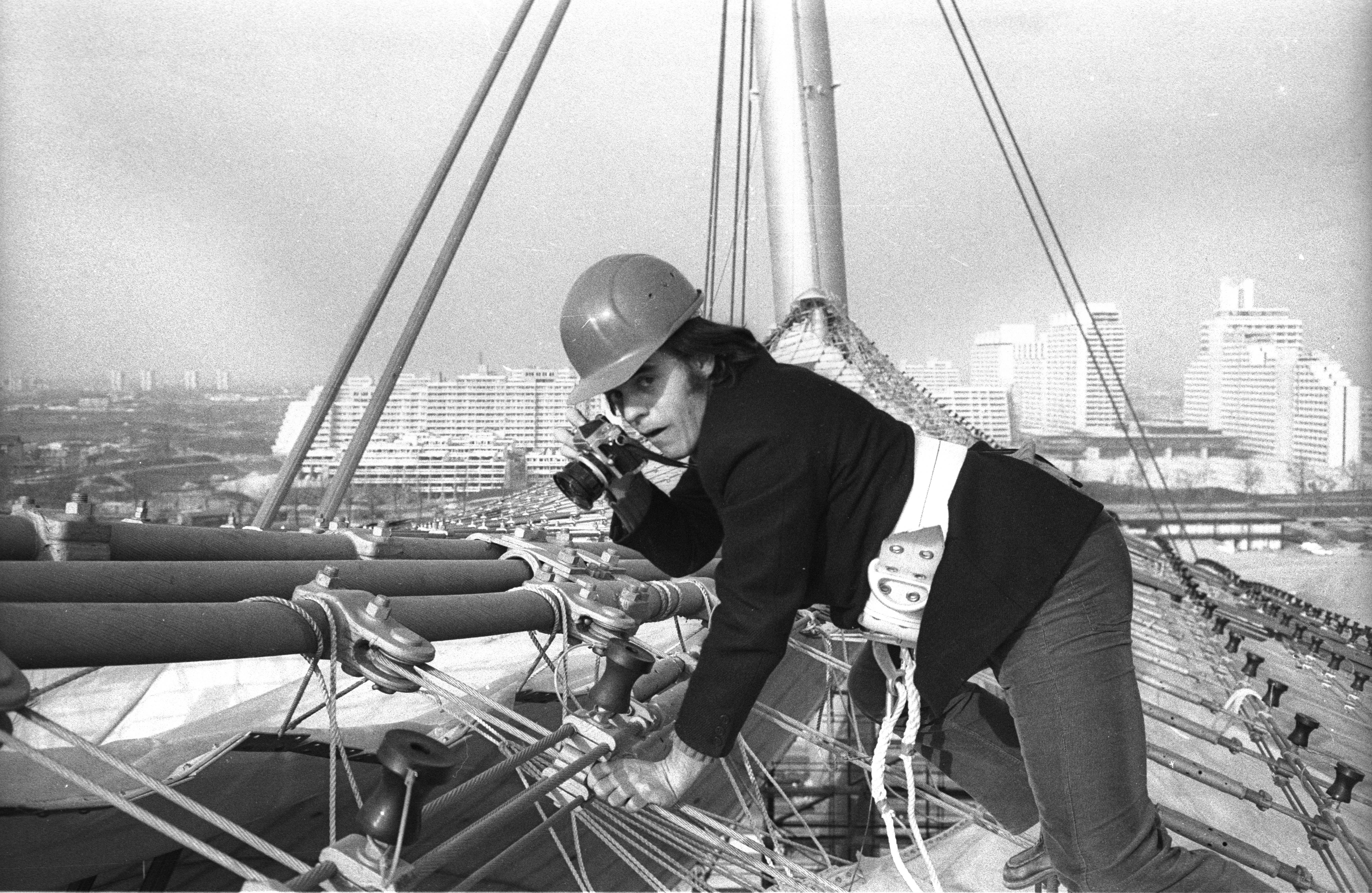 Der Fotograf Heinz Gebhardt mit dem Fotoapparat und angeseilt auf dem Zeltdach des Olympiageländes.