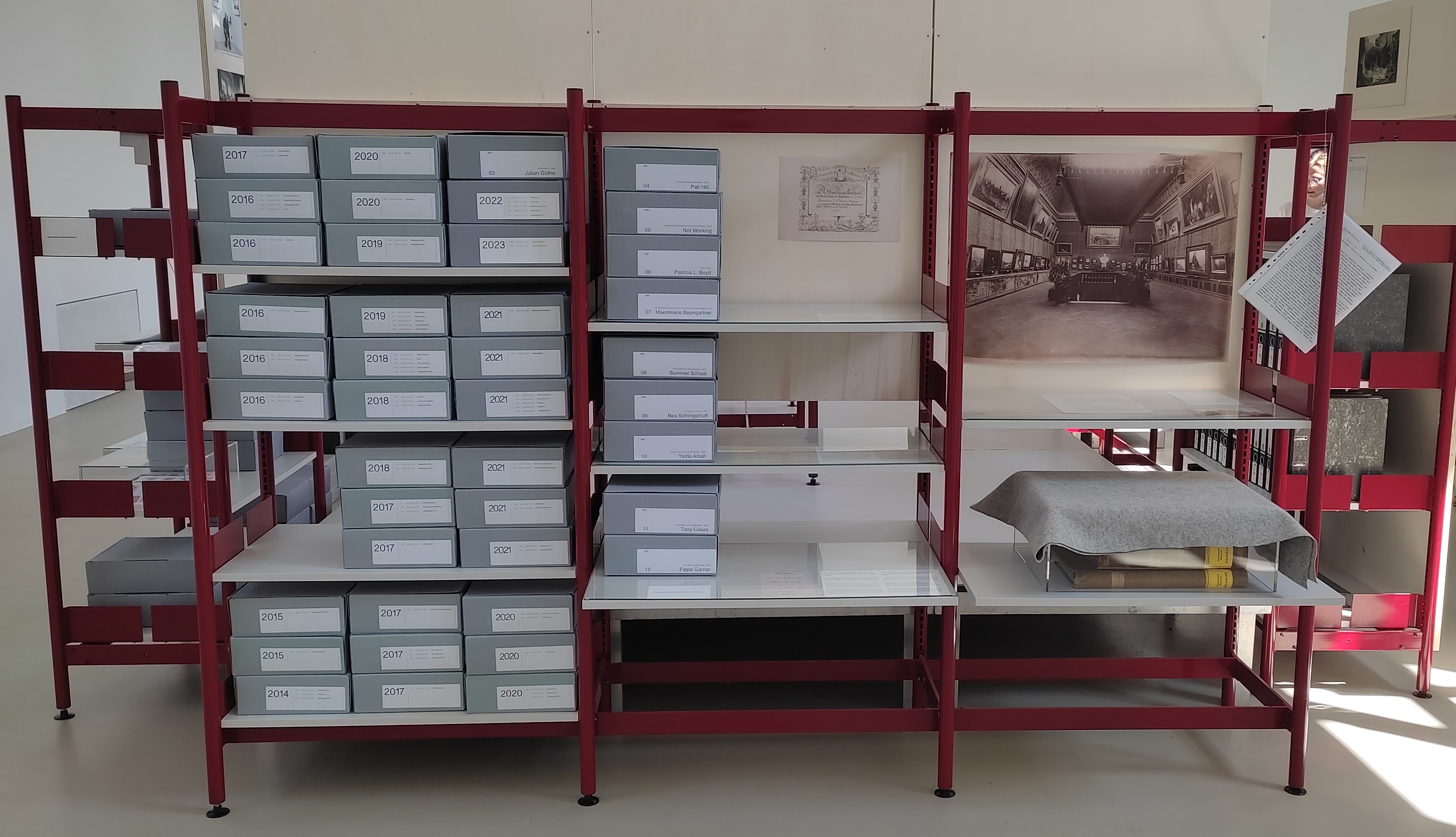 Blick auf die Ausstellungsinstallation mit Archivschachteln und abgedeckten Originalfolianten; Foto: Angela Stilwell.